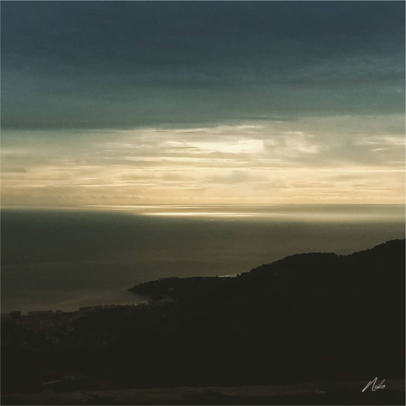 Photographie d'art en clair-obscur : mer et reliefs se fondant dans l'ombre, clarté diffuse à l'horizon