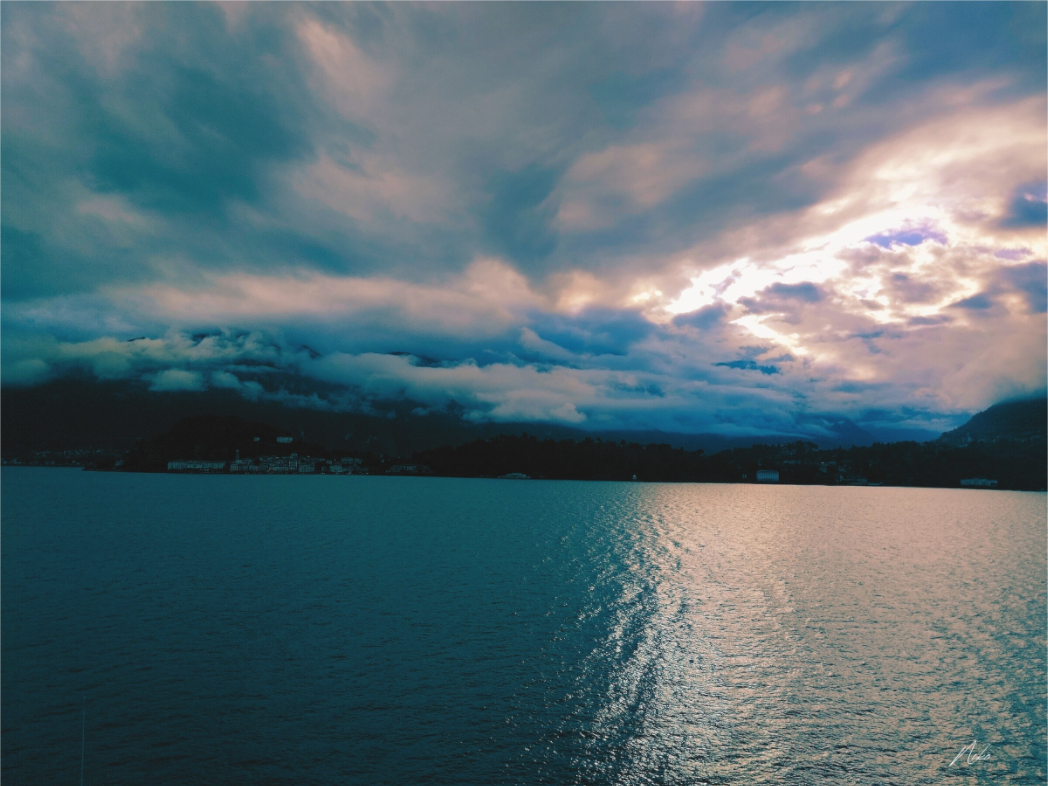 Photographie d'art de lac de montagne : trouée de lumière dans les nuages reflétée à la surface de l'eau