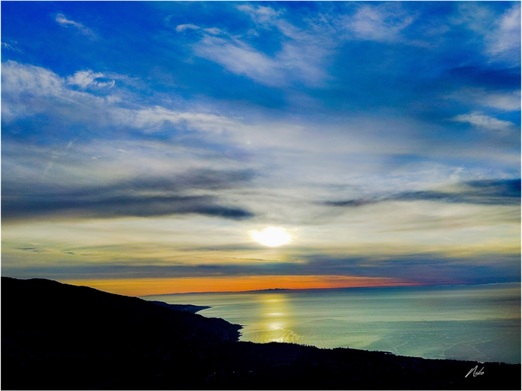 Photographie d'art de paysage : reliefs en silhouettes successives vers l'horizon où la mer et le ciel se rejoignent en bleu