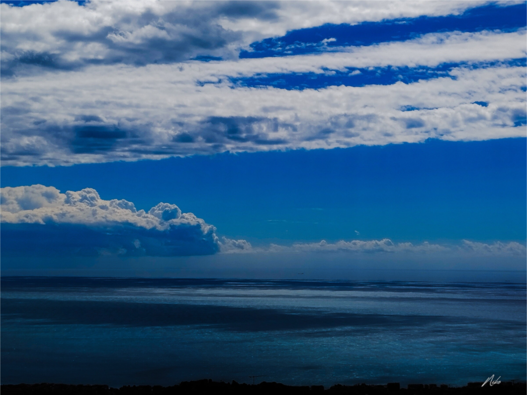 Photographie d'art marine : vastes étendues de bleu entre ciel et mer, nuages au-dessus de l'horizon