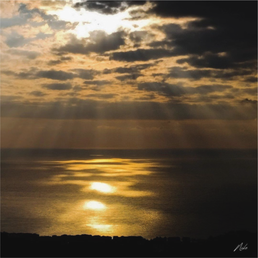 Photographie d'art en clair-obscur : lumière traversant les nuages sombres et se posant sur la mer