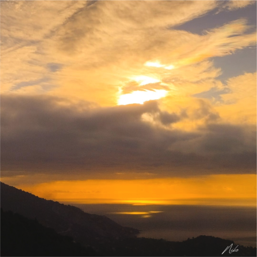 Photographie d'art de paysage : ciel embrasé à l'horizon, terre dans l'ombre et mince étendue de mer lumineuse