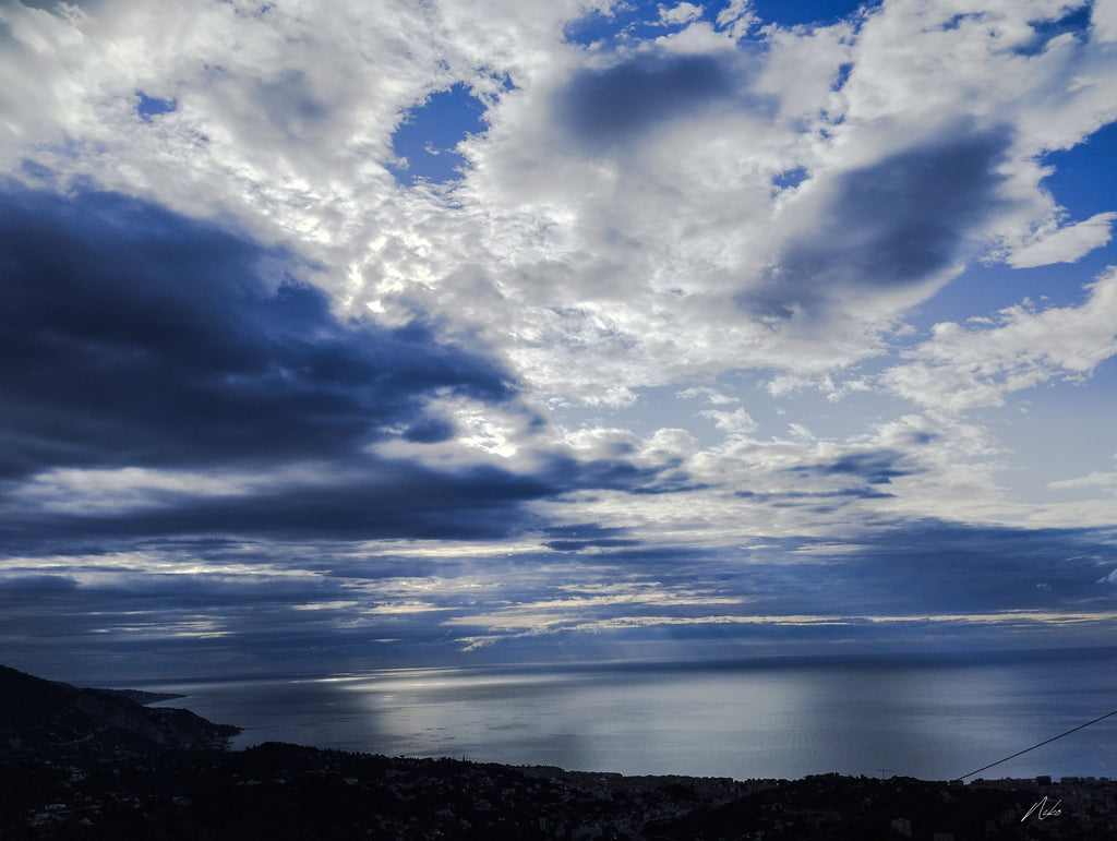 Photographie d'art marine : lumière traversant les nuages et se déployant à la surface de la mer